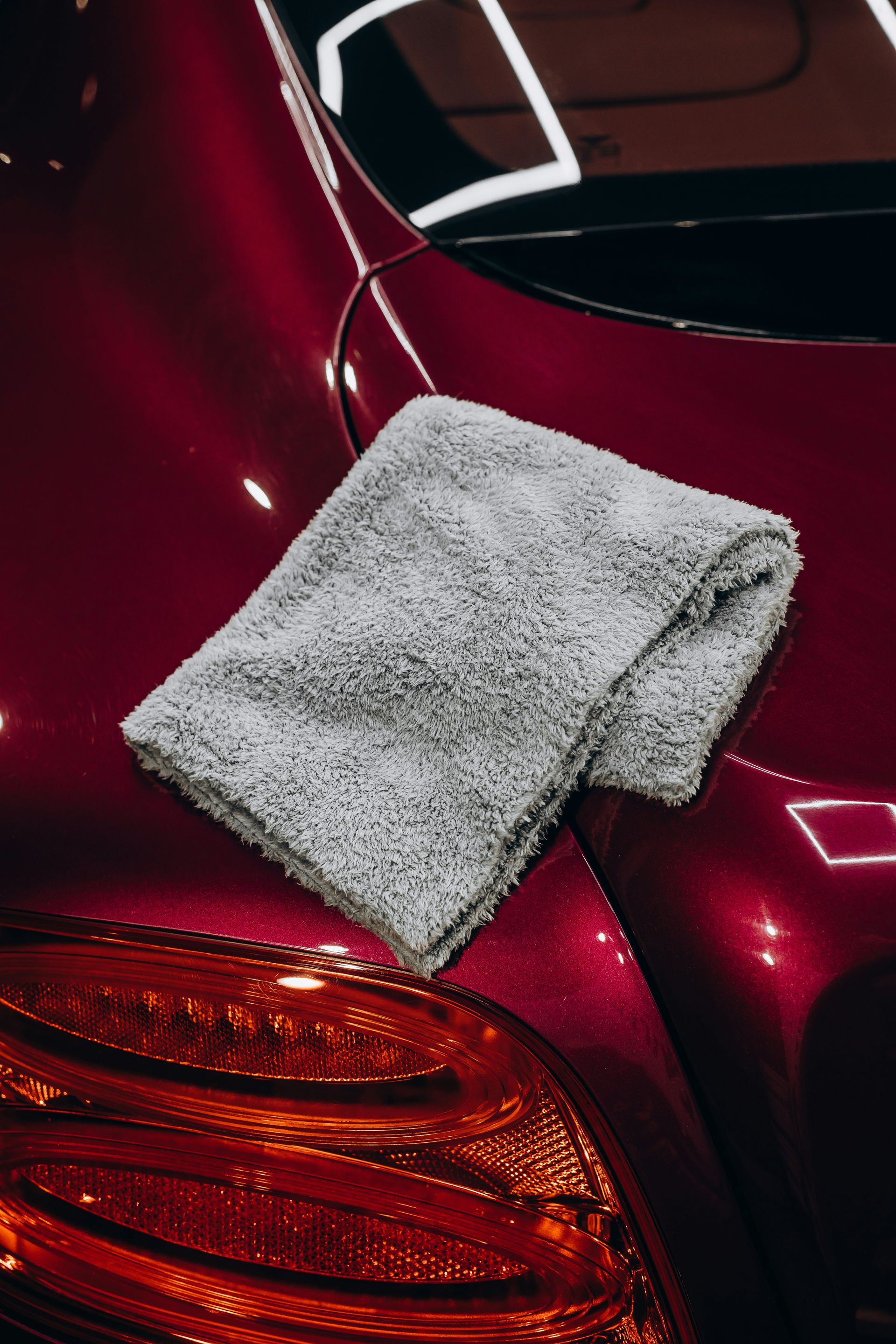 Gray microfiber cloth resting on a red car