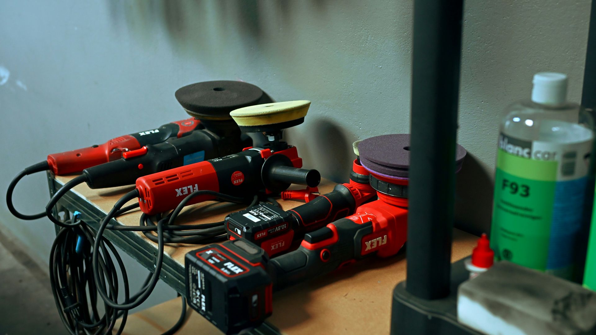 Several red car polishing tools on a shelf.