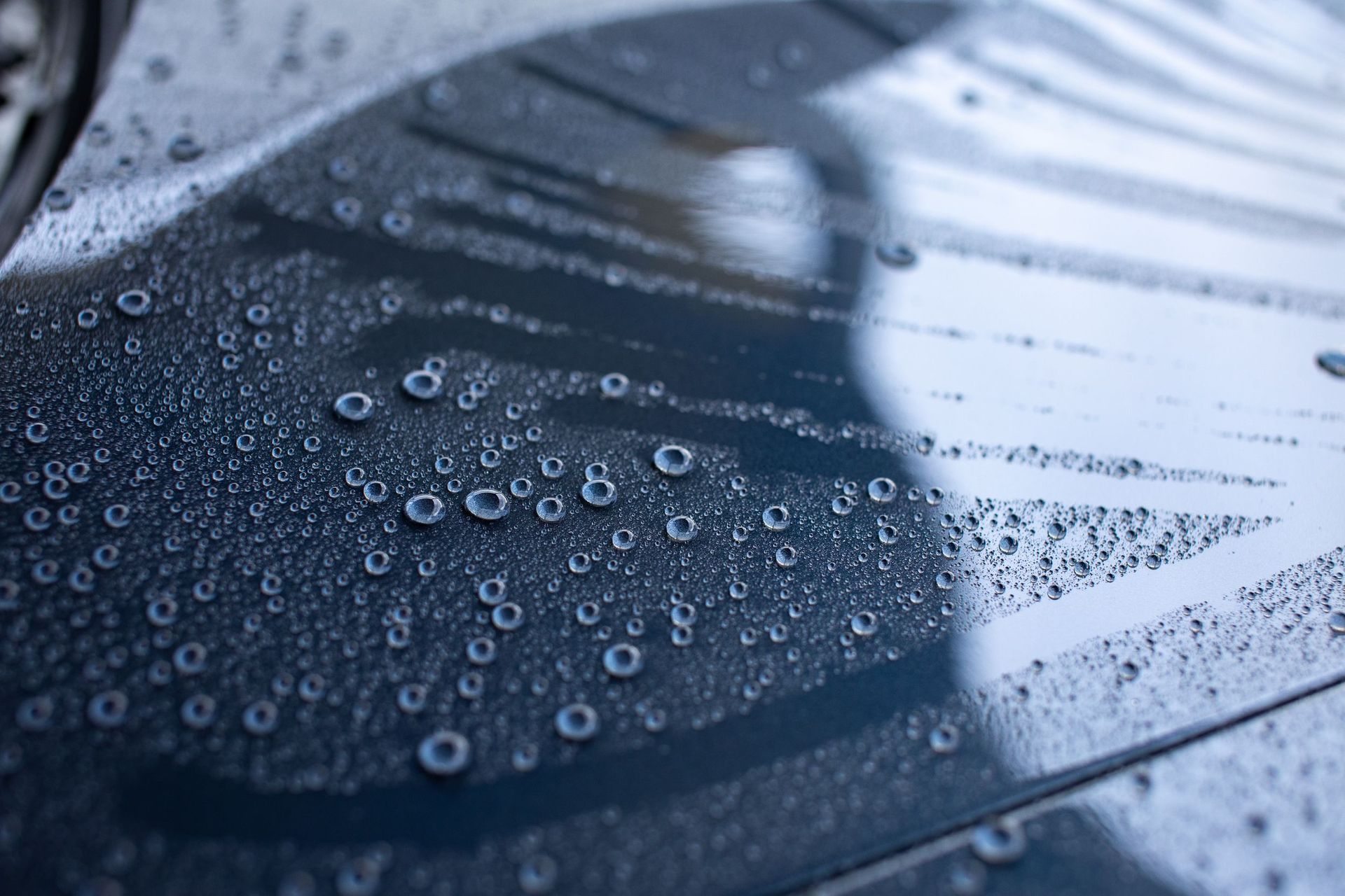 Detailed close-up of dew droplets on a reflective blue surface, creating a textured pattern.